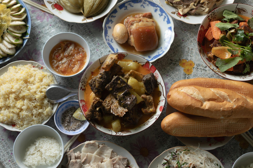 Hình ảnh mâm cơm ngày Tết truyền thống với nhiều món thịt, tinh bột và thức ăn đậm đà – minh họa nguy cơ “ăn dồn đạm” trong những ngày lễ đối với người bị gout.